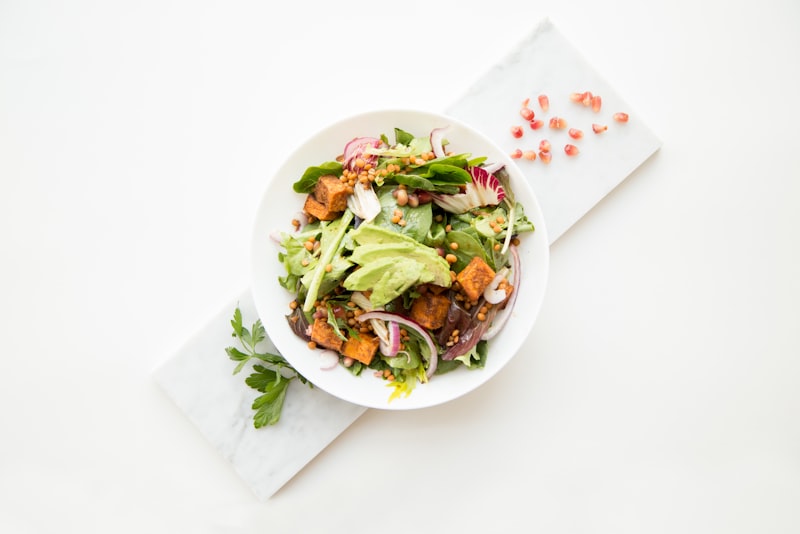 An overhead view of fresh vegetables, grains, and a portion of protein laid out on a counter for cooking